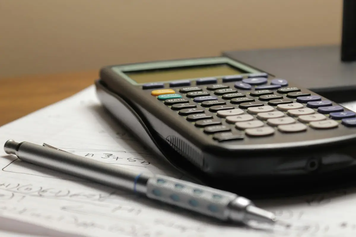 Calculadora e lapiseira sobre folhas de papel com anotações