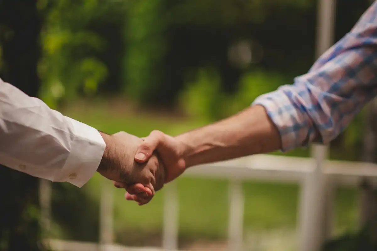 Duas pessoas apertando as mãos ao ar livre